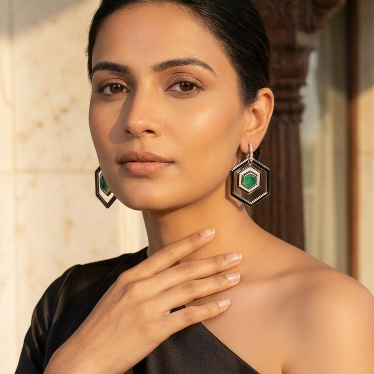 Woman wearing hexagonal earrings with green gemstones indoors.